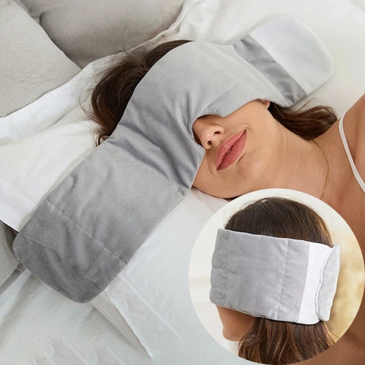 Woman lying down with a gray eye mask and pillow, with an inset showing the product. Weighted Eye Mask 